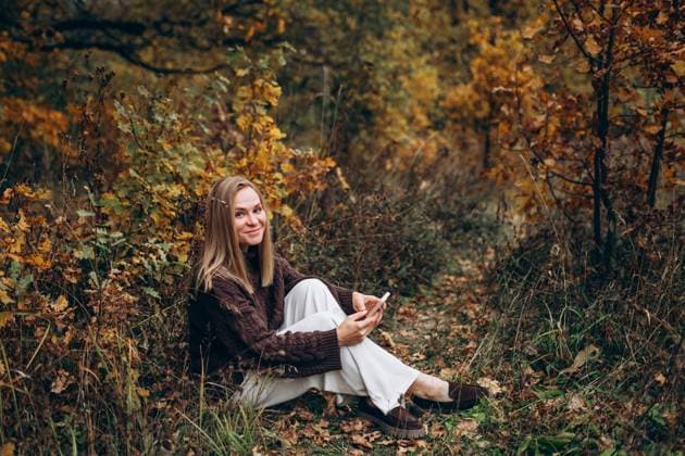 Woman in autumn forest using mobile phone and enjoying nature model released, Symbolfoto, MKVF00111