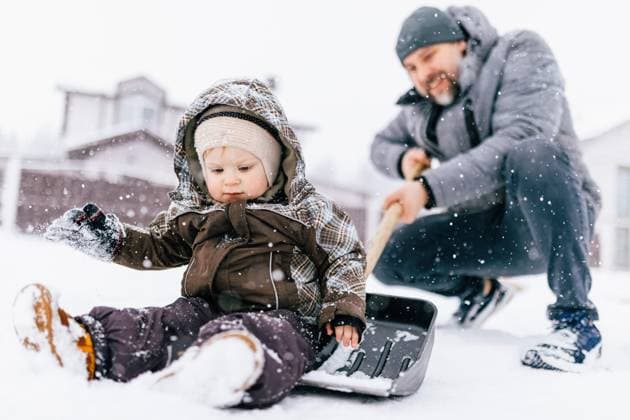 IMAGO Creative, Winter, In der Stadt Son and father playing with snow shovel outdoors in winter model released, Symbolfoto, NASF00058