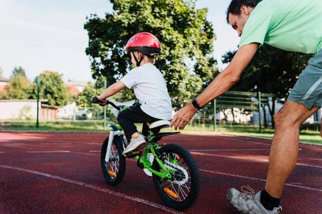 Father supporting son learning to ride bicycle outdoors model released, Symbolfoto, NDEF02934