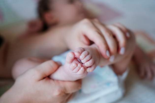 Mother gently holding baby foot in a close up showing comfort and care model released, Symbolfoto, NLAF00699