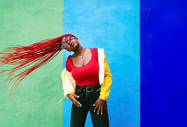 Stylish woman with red braids moving hair in front of colorful wall model released, Symbolfoto, SVCF00497