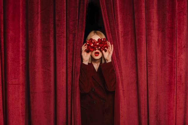 Person with gift bow posing behind red velvet curtain in festive mood model released, Symbolfoto, VSNF04353