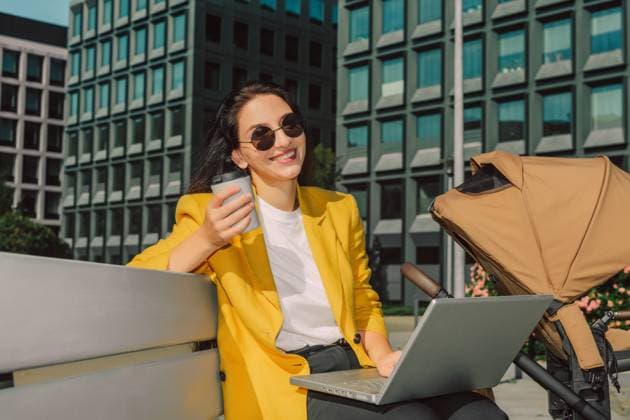 Businesswoman with coffee and laptop on bench near baby stroller outdoors model released, Symbolfoto, VSNF04396