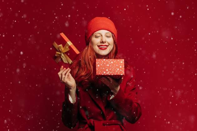 Smiling woman in red holding Christmas gift box with falling snow model released, Symbolfoto, VSNF04417
