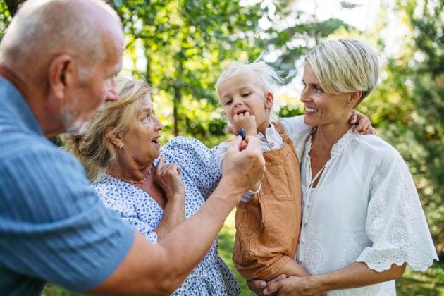 Smiling senior couple with grandchild and daughter at family gathering. Smiling senior couple with grandchild and daughter at family gathering, garden party. model released