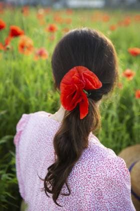 Eine Frau mit einer roten Mohnblume im Haar steht in einem Mohnfeld und genießt die Sommerlandschaft A woman with a red poppy in her hair, stands in a field of poppies, enjoying the summer scenery Copyright: imageBROKER SergiyxArtsaba ibxiqx14689868.jpg ,model released, Symbolfoto ,property released