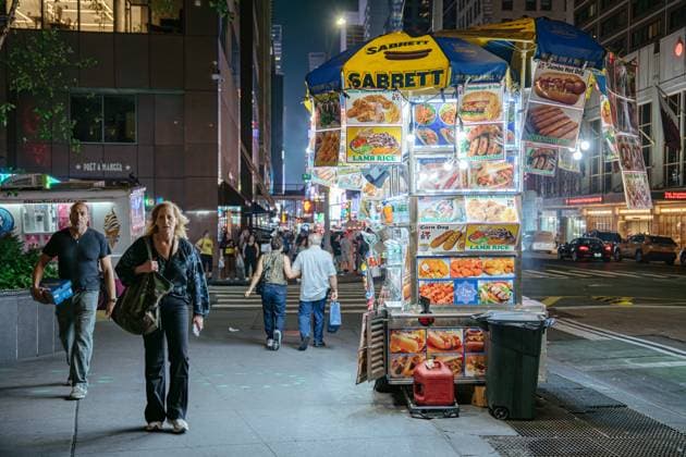 Bunter Street Food Cart am Times Square bei Nacht New York City, New York, USA - 07.31.2024: A vibrant Sabrett street food cart offers lamb rice, hot dogs, and corn dogs under bright lights in Times Square. Pedestrians pass by the busy sidewalk filled with energy and flavor in New York City. (License=RM) Copyright: xZoonar.com DenysxKovtunx 24107332