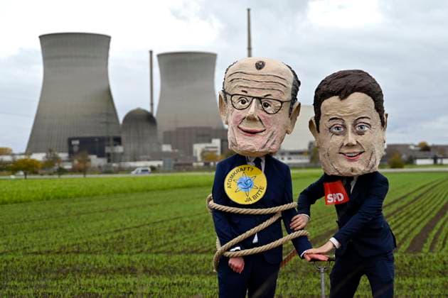 Die Kühltürme des Atomkraftwerk in Gundremmingen vor der Sprengung - Demonstranten mit Masken von Bundeskanzler Friedrich Merz (CDU) und Politiker Lars Klingbeil (SPD) posieren und fordern eine Umkehr in der Energiepolitik. Das AKW wird im Zuge des deutschen Atomausstieg 2025 gesprengt. Block A, erkennbar an der kleinen runden Kuppel, ist nach einem Störfall 1977 seit 1983 zurückgebaut. Block B und C mit den großen Kühltürmen sind seit 2017 bzw. 2021 vom Netz getrennt. (Themenbild, Symbolbild) Gundremmingen, 25.10.2025 Bayern Deutschland *** The cooling towers of the nuclear power plant in Gundremmingen before the demolition Demonstrators wearing masks of Federal Chancellor Friedrich Merz CDU and politician Lars Klingbeil SPD pose an Copyright: xDwixAnoraganingrumx