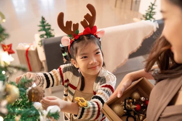 Festliche Momente. Kind schmückt Weihnachtsbaum mit Freude und Aufregung. A young girl adds ornaments to the Christmas tree, showcasing her excitement and the joy of holiday traditions with family. (License=RF) ,model released, Symbolfoto Copyright: xZoonar.com NATEExMEEPIANx 24162198 ,model released, Symbolfoto ,property released