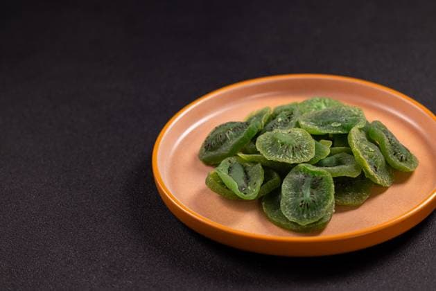 Getrocknete Kiwi-Scheiben auf einem braunen Teller Dried kiwi slices fanned on a rustic brown ceramic plate against a dark backdrop, vibrant green dehydrated fruit showcasing a healthy, sweet, vegan snack or baking ingredient (License=RF) Copyright: xZoonar.com VictoriaxKondysenkox(ArtSvitlynax 24165867
