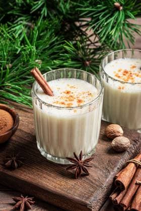 Eierlikör-Weihnachtscocktail-Getränk Eggnog drink (spiced egg-milk cocktail) with cinnamon for Christmas and winter holidays. Homemade eggnog in glasses with pine branches. (License=RF) Copyright: xZoonar.com OksanaxBratanovax 24188936