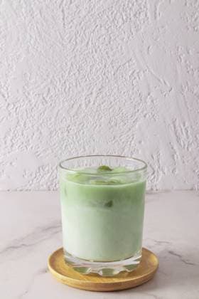 Ein großes Glas natürlichen Grüntee Matcha Latte steht auf einem Holzteller und einem weißen Marmortisch. Gesundheitsförderndes, belebendes Mittel A wide glass of natural green tea matcha latte stands on a wooden plate and a marble white table. health-improving, invigorating agent Copyright: imageBROKER MarinaxMoskalyuk ibxiqx14292192.jpg