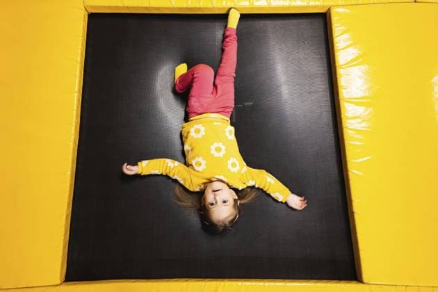 Das kleine Mädchen liegt kopfüber auf dem Trampolin im Spielpark. Kind in Bewegung bei aktiven Unterhaltungen Baby girl kid lies upside down on trampoline at playground park. Child in motion during active entertaiments Copyright: imageBROKER ASxPHOTOFAMILY ibxiqx15392346.jpg ,model released, Symbolfoto ,property released