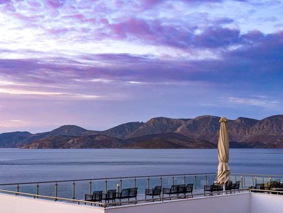 Sonnenliegen und Sonnenschirm auf einer Terrasse mit Meerblick bei Sonnenuntergang auf der Insel Kalymnos in Griechenland Mountains and the sea can be seen in the background under a purple-blue sky (License=RF) Copyright: xZoonar.com SandraAlkadox 24205115