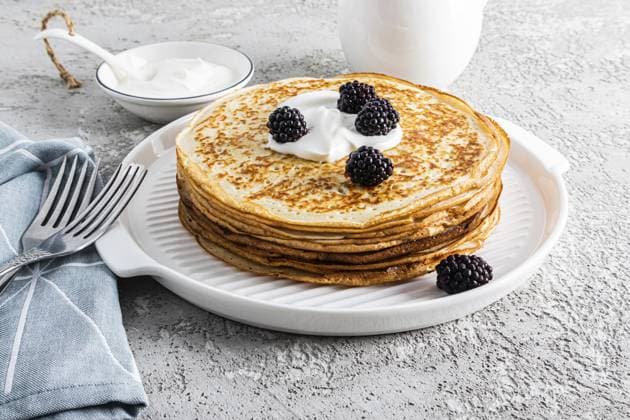 Ein großer Stapel köstlicher heißer Pfannkuchen mit saurer Sahne und Brombeeren auf einem schönen weißen Serviertablett mit Besteck und einem Grundstück. View from front A large stack of delicious hot pancakes with sour cream and blackberries on a beautiful white serving tray with cutlery and a plot. Front view Copyright: imageBROKER MarinaxMoskalyuk ibxiqx14292238.jpg
