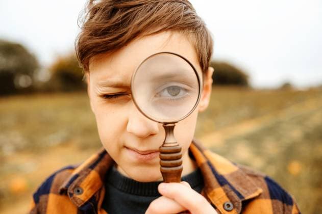 Boy looking through magnifying glass in open field. Northampton, England, United Kingdom CR_JNDO251030A-1867933-01 ,model released, Symbolfoto