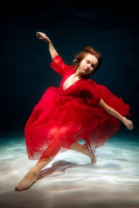 Dancer in red dress gracefully swimming underwater at a deep pool Saint Petersburg, Saint Petersburg, Russia CR_KNCD251101-1875092-01 ,model released, Symbolfoto