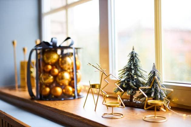 Luxurious interior of the room for Christmas and New Year. Festively decorated windowsill illuminated by daylight, gift box with golden balls, figurines and candles, property released, , 61427974.jpg RECORD DATE NOT STATED