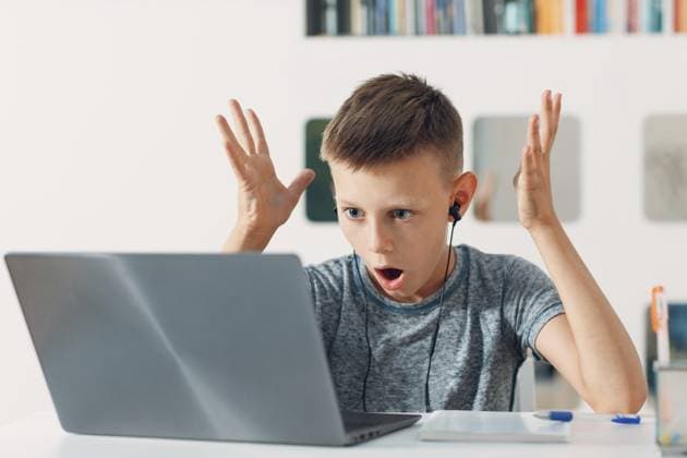 Junge mit Headset sitzt mit Laptop am Tisch und bereitet sich auf die Schule vor. Konzept der Online Bildung Young boy in headset sitting at table with laptop and preparing to school. Online education concept Copyright: imageBROKER Max ibxiqx15477394.jpg ,model released, Symbolfoto ,property released