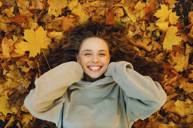 Lächelnde junge Frau, die auf dem Herbstlaub im Wald mit den gelben Blättern liegt Smiling young woman lying on the autumn foliage in the forest with the yellow leaves Copyright: imageBROKER Maxx4e ibxiqx15483052.jpg ,model released, Symbolfoto ,property released