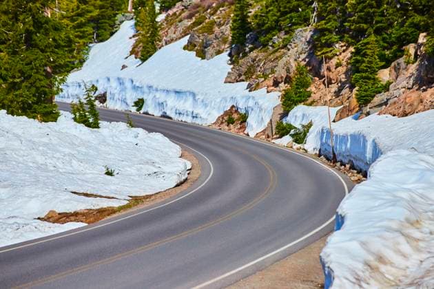 Winding Snowy Mountain Road in Crater Lake National Park Eye Level Perspective Winding mountain road at Crater Lake National Park, Oregon, flanked by towering snow banks and evergreen trees. A breathtaking winter landscape that invites adventure and explores natural beauty., 60924272.jpg RECORD DATE NOT STATED