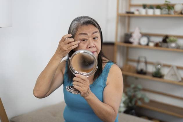 Eine ältere Frau, die einen Wellness Ansatz verfolgt, indem sie sich um ihr Aussehen vor einem Spiegel kümmert und zu Hause Selbstliebe und Selbstvertrauen fördert An elderly woman adopting a wellness approach by caring for her appearance in front of a mirror, fostering self-love and confidence at home Copyright: imageBROKER NATEExMEEPIAN ibxiqx15517932.jpg ,model released, Symbolfoto ,property released