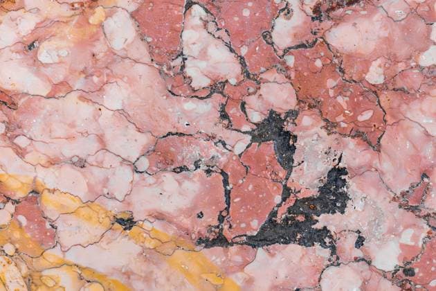 Natural marble texture with pink and yellow hues Close-up of a textured marble surface featuring a fusion of pink and yellow hues, accentuated by contrasting dark veins, offering an intricate and organic pattern. Model Released HodeiUnzueta_ID32002_1089544_021 Copyright: xHodeixUnzuetax