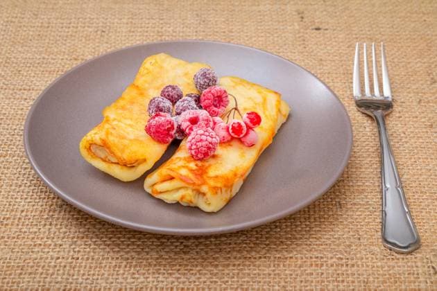 IMAGO Creative, Food, High Protein Frühstück Homemade pancakes and frozen raspberries on plate. Homemade pancakes topped with frozen raspberries and blackberries on the plate with the fork on the sackcloth., 63124372.jpg RECORD DATE NOT STATED