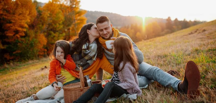 Parents with young children sitting outdoors in autumn light. Parents with young children sitting outdoors in autumn light, having picnic. model released