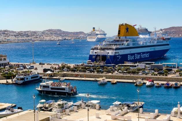 Mykonos, Kykladen, Griechenland - Mykonos New Port, eine Faehre der Blue Star Ferries liegt am Kai im neuen Hafen vor der Skyline von Mykonos-Stadt. Vorne ein Taxi-Boot ein Sea Bus bringt die Touristen in die Altstadt. Hinten weitere Kreuzfahrtschiffe liegen in der Bucht vor Mykonos-Stadt mit Blick auf die Altstadt mit den Windmuehlen. Tenderboote bringen die Touristen in die Altstadt. Mykonos Mykonos Griechenland *** Mykonos, Cyclades, Greece Mykonos New Port, a ferry of the Blue Star Ferries lies at the quay in the new harbor in front of the skyline of Mykonos town In front a cab boat a sea bus brings the tourists to the old town In the back more cruise ships are moored in the bay in front of Mykonos town with a view of the old town with