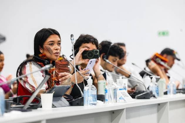 November 11, 2025, Belem, Brazil, Brazil: A Brazilian Indigenous delegate with traditional face paint and tattoos reads from her phone while speaking during a session on Indigenous and tribal representation at COP30 in Belem, Brazil. The 2025 conference highlights the active participation of Indigenous communities in climate discussions, with speakers blending cultural identity and modern tools of communication. Belem Brazil - ZUMAo116 20251111_znp_o116_029 Copyright: xBiancaxOterox