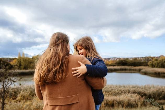 Mother and daughter hugging by a calm lake surrounded by autumn trees. Corby, England, United Kingdom R_JNDO251110-1878616-01 ,model released, Symbolfoto