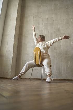 Junge kaukasische Frau sitzt rückwärts auf einem Stuhl mit erhobenen Armen in ungezwungener Innenumgebung Young caucasian female sitting backwards on chair with arms raised in casual indoor setting Copyright: imageBROKER ElenaxSafonova ibxiqx15551268.jpg ,model released, Symbolfoto ,property released