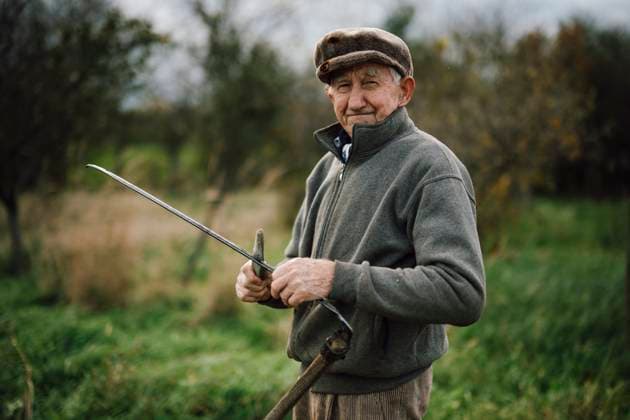 Elderly farmer holds a tool in a lush green field Malo Laole, Brani?evo District, Serbia CR_NEST251117-1896731-01 ,model released, Symbolfoto