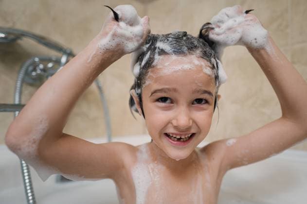 Smiling child washing hair with shampoo foam in bathtub at home model released, Symbolfoto property released, ANAF05230