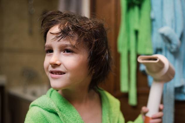 Child with wet hair in green bathrobe using hair dryer in bathroom model released, Symbolfoto property released, ANAF05240
