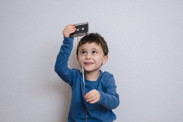 Child playing with retro audio cassette indoors and smiling model released, Symbolfoto property released, ANAF05257