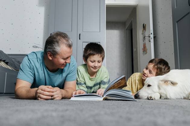 Father and children reading a book together with dog at home model released, Symbolfoto property released, ELMF01239