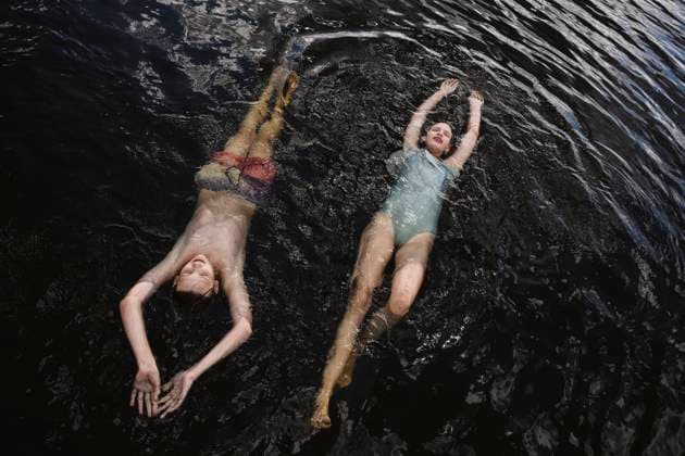 Teens floating and smiling in summer lake wearing swimsuits model released, Symbolfoto, EYAF03632