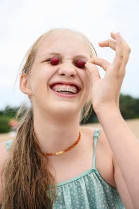 Smiling girl with dental braces and berries enjoying fun outdoors in summer model released, Symbolfoto, EYAF03722