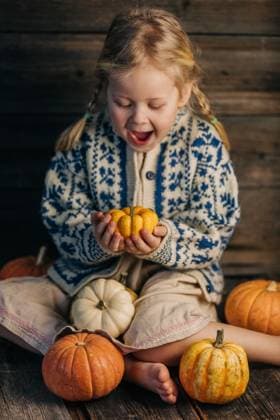 Child in cozy sweater holding pumpkin indoors in autumn harvest mood model released, Symbolfoto, NASF00080