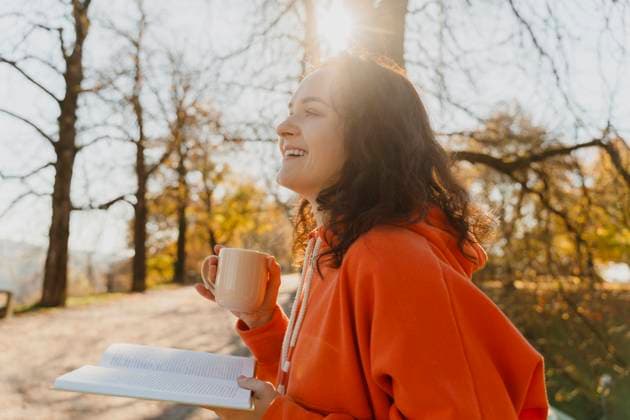 Woman relaxing with book and tea outdoors in autumn park model released, Symbolfoto, NDEF03009