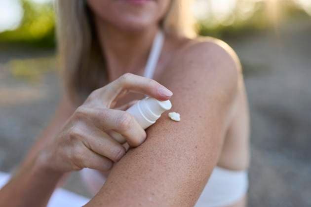 Woman applying sunscreen on arm outdoors in summer for skin care model released, Symbolfoto, PNEF03564
