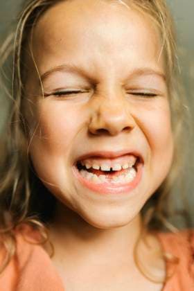 Child laughing and smiling with missing baby tooth in close up portrait model released, Symbolfoto property released, VIVF01722