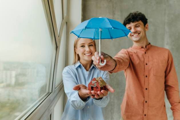 Couple protecting house model with umbrella indoors showing happiness model released, Symbolfoto property released, YTF04270
