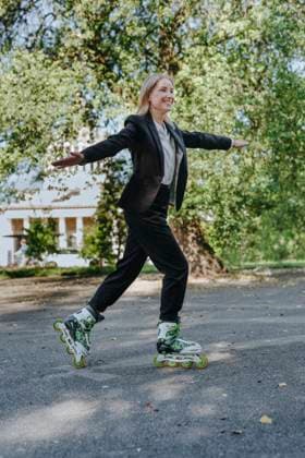 Businesswoman in suit roller skating outdoors balancing arms in park model released, Symbolfoto, YTF04375