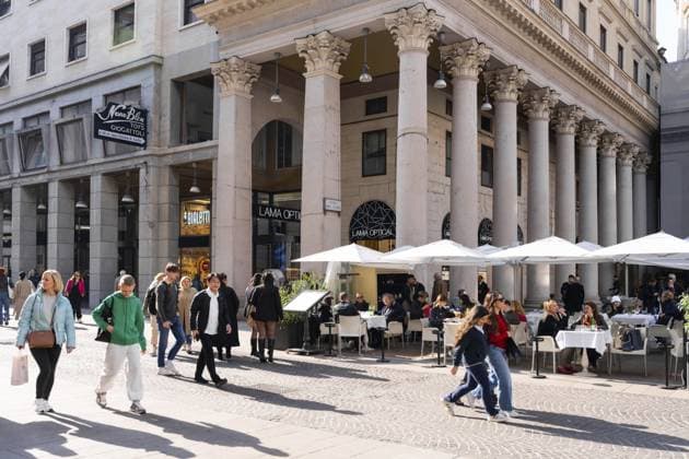 Mailand, Italien — 08. April 2025: Ladenfronten von Lama Optical und Bialetti unter einer klassischen Kolonnade mit Leuten, die im Café essen und an sonnigen Tagen in Mailand vorbeigehen Milan, Italy - April, 08, 2025: Lama Optical and Bialetti storefronts under classic colonnade with people dining at cafe and walking by on sunny day in Milan Copyright: imageBROKER IgorxZakirov ibliqx15561390.jpg