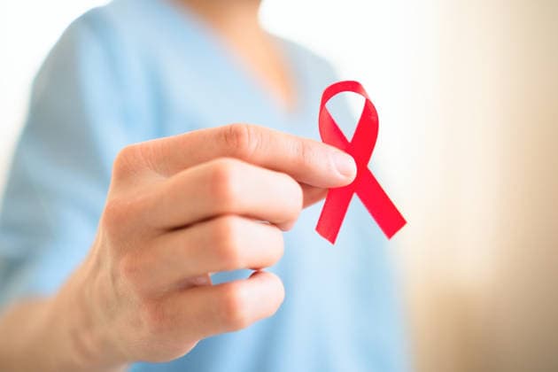 Nahaufnahme Hand hält rote AIDS-Schleife Extreme close up of female hand holding red satin awareness ribbon, symbolizing HIV AIDS solidarity, support and hope for future treatment. (License=RF) ,model released, Symbolfoto Copyright: xZoonar.com elenaxskorobogatovax 24267163 ,model released, Symbolfoto ,property released