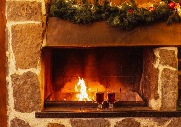 Zwei Gläser mit Glühwein stehen neben dem Kamin. Weihnachtsschmuck und Tassen mit einem würzigen Heißgetränk. Offenes Feuer und Steinmauern. Silvester. Zwei Gläser mit Glühwein stehen neben dem Kamin. Weihnachtsschmuck und Tassen mit einem würzigen Heißgetränk. Offenes Feuer und Steinmauern. Silvester. (License=RF) Copyright: xZoonar.com DashaxPetrenkox 24268688