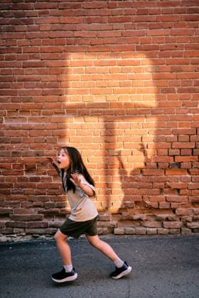 Das Mädchen rennt vor Angst vor dem Schatten an der Wand weg Child runs away in fear on a city street, sun casting dynamic shadows on the old brick wall (License=RF) ,model released, Symbolfoto Copyright: xZoonar.com MAREVGENNAx 24305268 ,model released, Symbolfoto ,property released